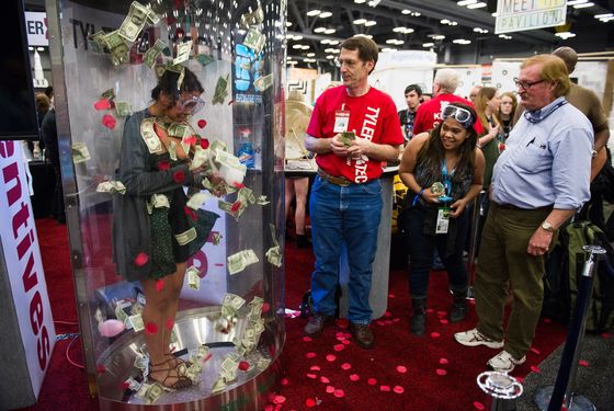 An attendee attempts to grab U.S. one-dollar bills in a promotional booth at the South By Southwest (SXSW) Interactive Festival in Austin, Texas, U.S., on Tuesday, March 11, 2014. 