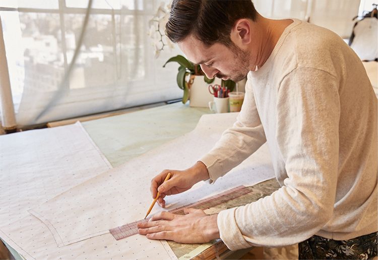 Man tracing outline on paper dress mock