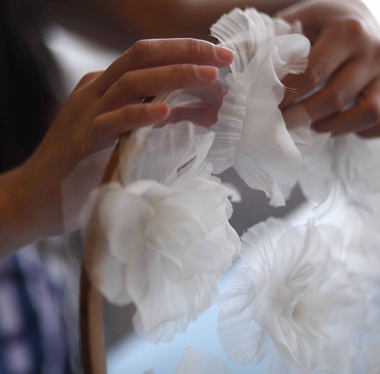 Woman attaches fabric flowers to a dress form