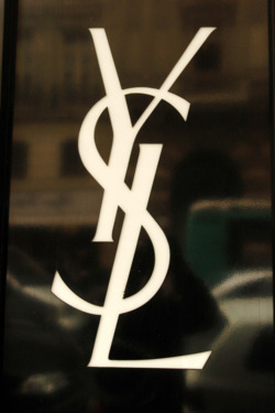 View of the Yves Saint-Laurent logo at a closed shop in central Paris on June 5, 2008 as a funeral mass for the French fashion designer is held nearby at Saint-Roch church. In homage to its founder, YSL shops worldwide were due to close for two hours. Saint Laurent, one of the 20th century's greatest couturiers, credited for revolutionising women's wardrobes, died on June 1, aged 71 of a brain tumour. 
AFP PHOTO JEAN AYISSI (Photo credit should read JEAN AYISSI/AFP/Getty Images)