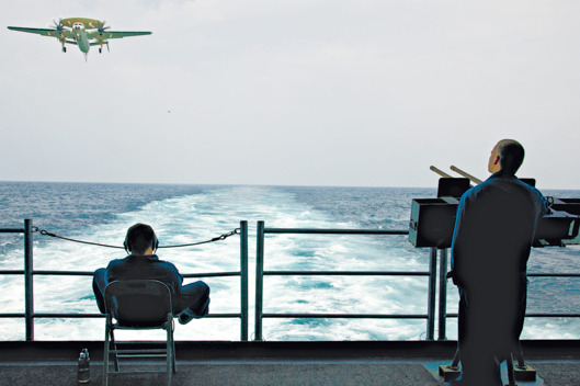 USA. American aircraft carrier USS George H W Bush. NImitz class. Nuclear powered with a crew of sailors and airmen of over 5,000. Somewhere in the Arabian Gulf. A radar surveillance aircraft comes in to land approaching the rear of the ship.