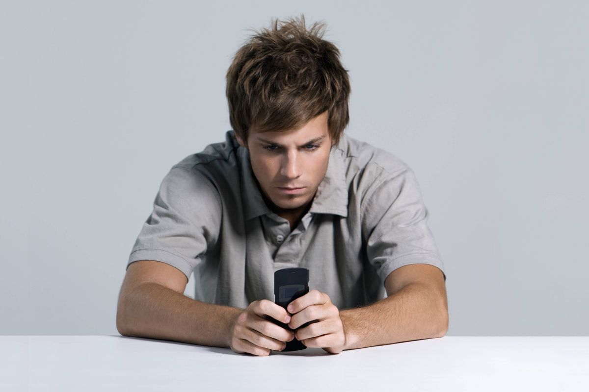 Young man text messaging with cell phone, furrowing brow --- Image by © Matthieu Spohn/Ës/Corbis