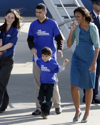 First lady Michelle Obama walks with Cpl. Tiffany Garcia and her husband Omar Garcia and their children Joel, 4, left, and Omar, 5, from The Mission Continues during her arrival at Lambert St. Louis International Airport, Monday, March 5, 2012, in St. Louis. The Mission Continues is a national nonprofit organization challenging post-9/11 veterans to serve and lead in their communities.