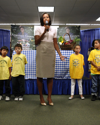 Surrounded by school children, First lady Michelle Obama speaks to a waiting crowd before signing copies of her book