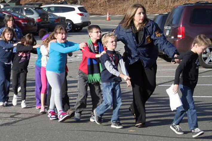 In this photo provided by the Newtown Bee, Connecticut State Police lead children from the Sandy Hook Elementary School in Newtown, Conn., following a reported shooting there Friday, Dec. 14, 2012. (AP Photo/Newtown Bee, Shannon Hicks) MANDATORY CREDIT