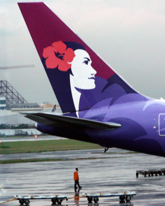 A worker stands next to the tail of a Hawaiian Airlines aircraft parked at Manila international airport on June 16, 2008. AFP PHOTO/TED ALJIBE (Photo credit should read TED ALJIBE/AFP/Getty Images)