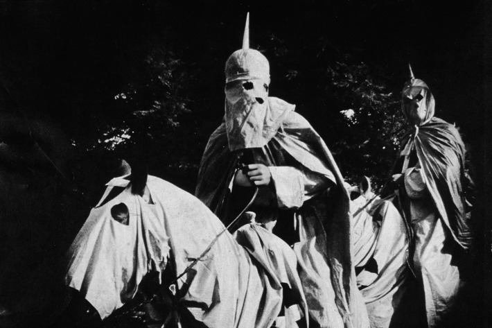 Actors costumed in the full regalia of the Ku Klux Klan ride on horses at night in a still from 'The Birth of a Nation,' the first-ever feature-length film, directed by D. W. Griffith, 1914.