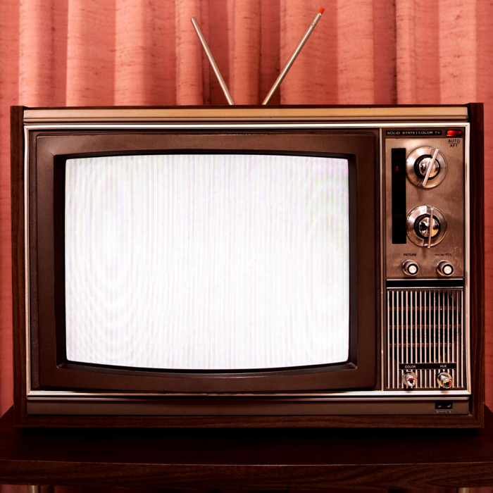 Old television on stand, in front of curtain