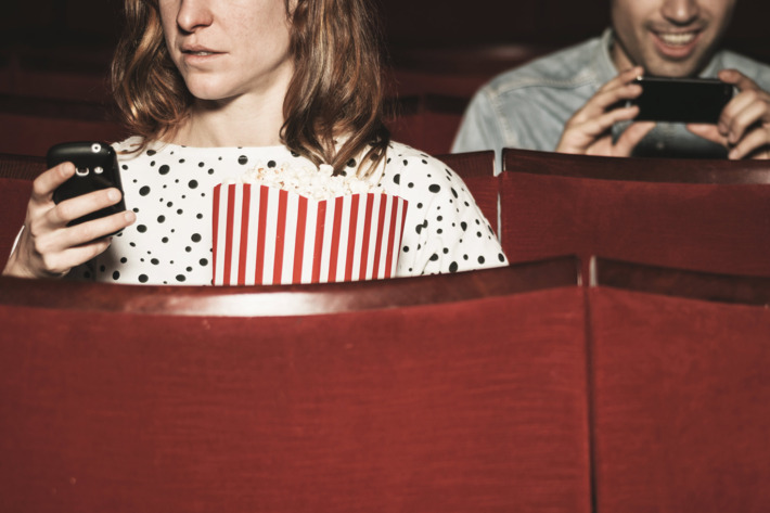 Man and woman using their phones in theater