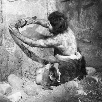 CAVEMAN CARVING ON CAVE WALL