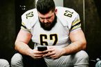 Football player looking at smartphone before game